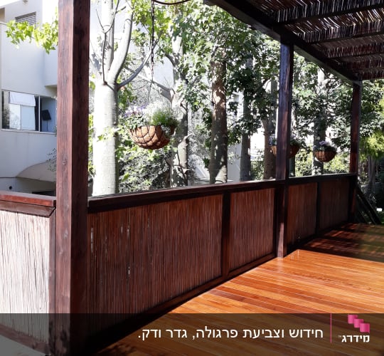 מרפסת עץ עם גג קנים ועציצים תלויים
